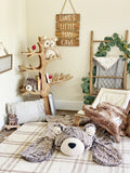 A plush bear rug on the floor of a woodland themed nursery with a tree shaped wooden sculpture and wooden ladder in the background.