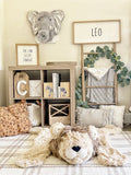 A plush lion rug made by ClaraLoo in a safari themed nursery. The lion rug features plush tan colored faux fur with a crocheted face and ears.