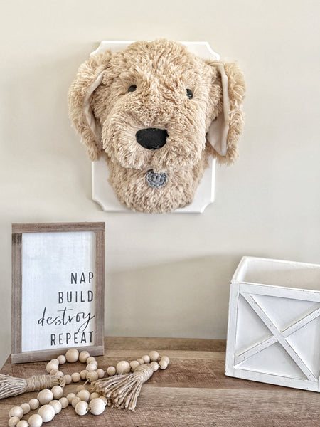 A plush Puppy Dog Wall Mount handmade by ClaraLoo in an animal themed nursery. This stuffed dog is made with soft tan faux fur and crocheted accents. This plush puppy is mounted on a white wooden plaque.