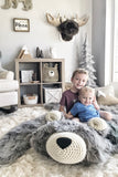 Two children sitting on a large gray bear rug made by ClaraLoo in a woodland themed bedroom.