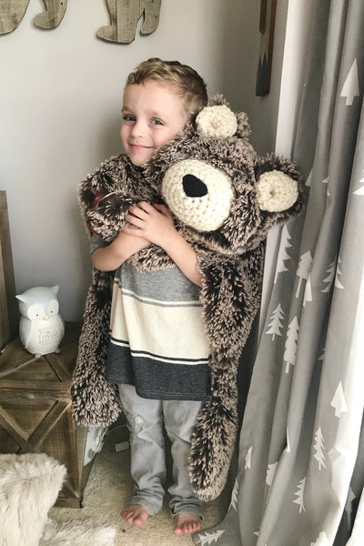 Child holding a large plush bear rug made by ClaraLoo in a woodland themed bedroom.