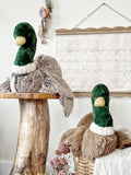 Two stuffed mallard ducks with green heads and brown bodies on a wooden surface.