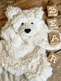 A plush white polar bear lovey made by ClaraLoo with soft faux fur and crocheted accents.