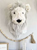 A plush lion wall mount handmade by ClaraLoo with soft white and gray faux fur with crocheted accents. This stuffed faux taxidermy lion is mounted on a white wooden plaque.