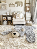 A woodland themed nursery with a plush bear rug made by ClaraLoo on the floor. The bear rug has plush gray faux fur with a cream colored face and ears.