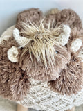 A handmade highland cow lovey by ClaraLoo. This plush highland cow features soft brown faux fur with crocheted accents.